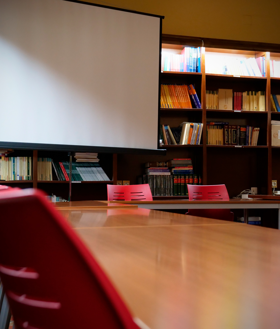 Imagen de uno de los espacios de reunión disponibles en la Facultad de Derecho, cuenta con diversas sillas y un proyector